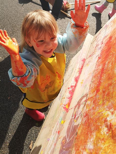 Vaiko ranka laiko pieštuką, piešiantis mokyklos pastatą