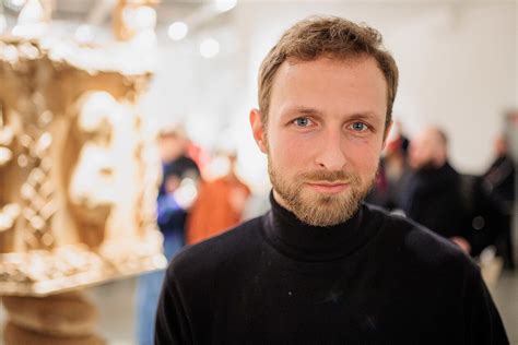 Skulptorius Mykolas Sauka dirbtuvėje su medžio skulptūra