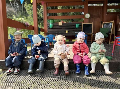 vaikų grupė žaidžianti su vaikiškais traktoriukais