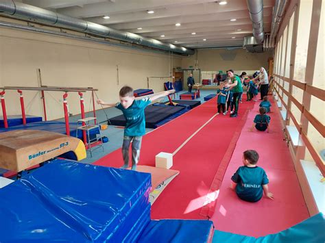 vaikai gimnastikos salėje su treneriu