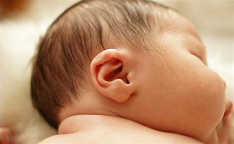 Naujagimis, laikomas gydytojo rankose