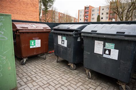 Nuotrauka su nepatogiai pastatytais šiukšlių konteineriais