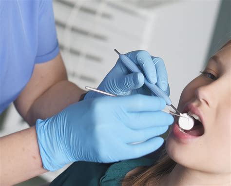 Vaikų odontologas apžiūri kūdikio burną