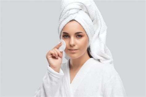 Moterys naudoja micelinį vandenį ir prausiklį veidui valyti