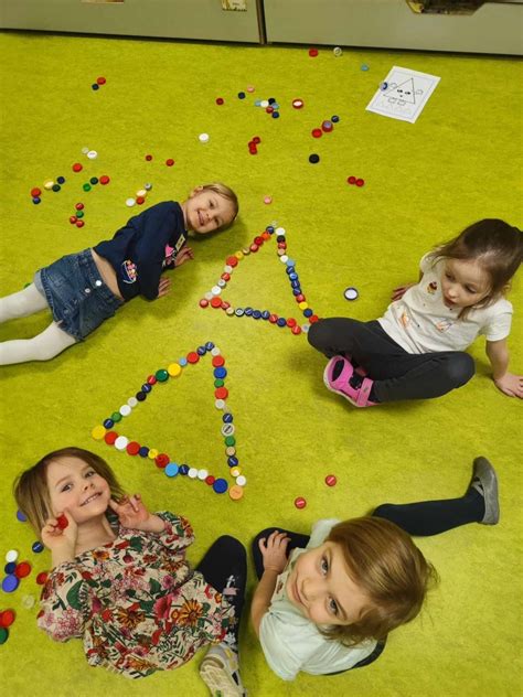 vaikai klijuoja aplikaciją iš geometrinių figūrų