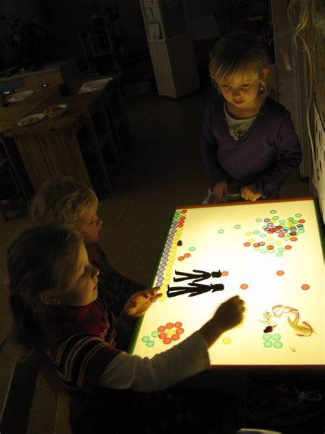 vaikai ant šviesos stalo ieško geometrinių figūrų