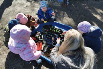 Nuotrauka, vaizduojanti vaikus, žaidžiančius ir mokymosi lauko darželyje.