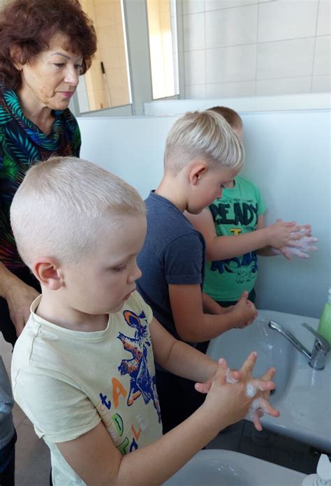 Vaikai atlieka rankų plovimo eksperimentą su UV lempa