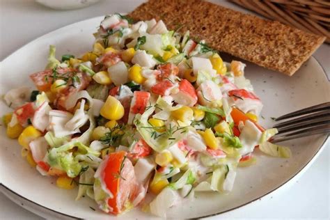 Estetiškai patiektos krabų lazdelių salotos šventiniame inde