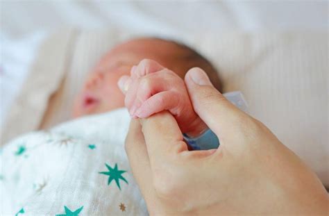 Moteris su kūdikiu, dėvinti žindymo karolius
