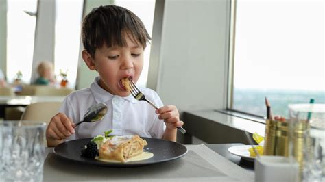 vaikas sėdi prie stalo ir piešia