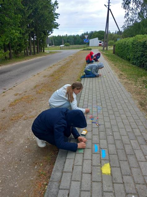 Vaikai, piešiantys lauke su kreidelėmis ant asfalto