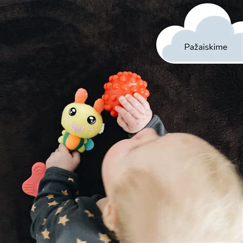 kūdikis bando sugriebti žaislą
