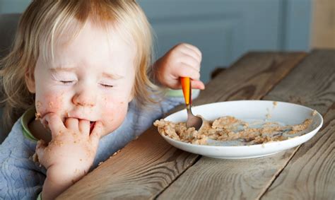 Vaikas valgo košę iš šaukštelio