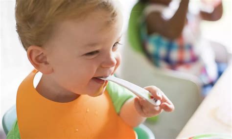 Kūdikis sėdi tiesiai ir siekia maisto