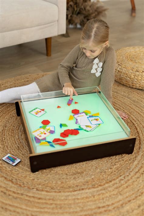 vaikai žaidžia su smėliu ant šviesos stalo