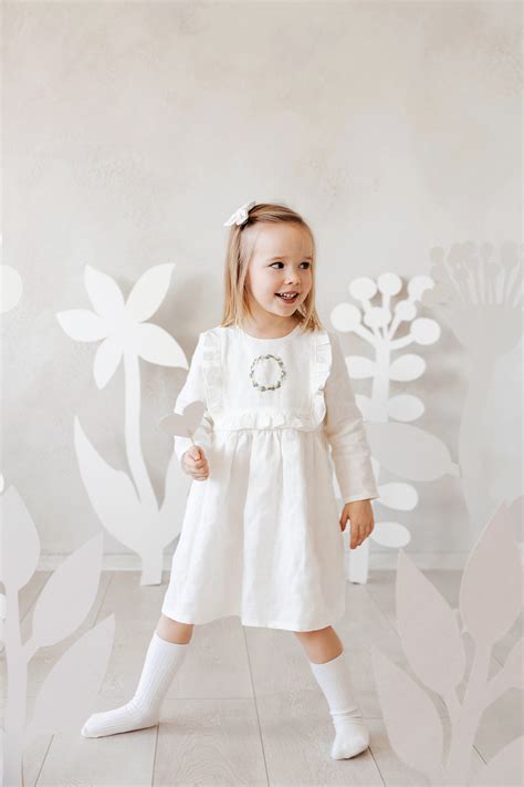 mergaitė dėvi baltą suknelę krikštynoms