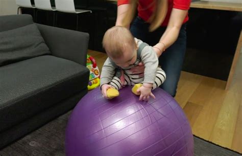 Motina daro pratimus su kūdikiu ant gimnastikos kamuolio