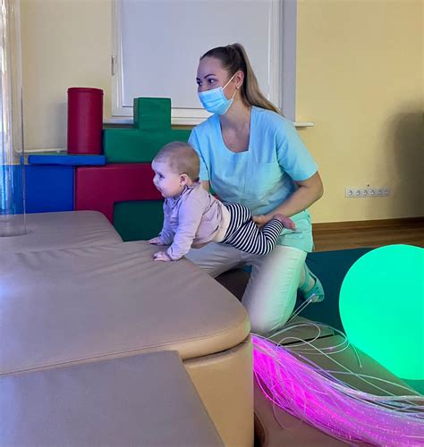 Kūdikis daro pratimus su kineziterapeutu