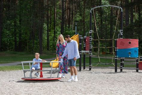 Vaizdas su vaikais žaidžiančiais lauke prie darželio