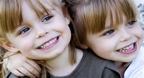 Dvi skirtingos mergaitės žaidžiančios kartu, viena jų šypsosi, kita stebi