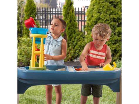 vaikas žaidžia su vandens ir smėlio stalu