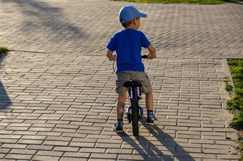 vaikas su šalmu ir apsaugomis ant triračio paspirtuko