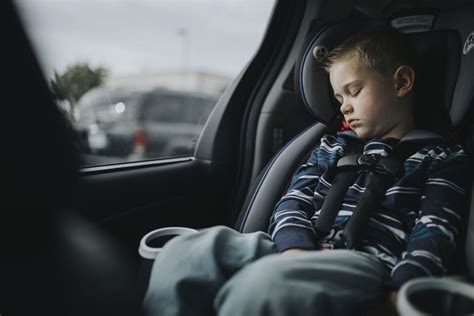 vaikas miega kelioninėje pagalvėlėje automobilyje