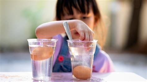 Vaikas atlieka eksperimentą su vandens sūkuriu stiklainyje