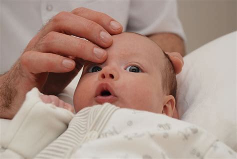 Osteopato rankos dirbančios su kūdikio galva